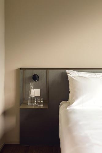 a bed with a nightstand next to a white bed at Hotel Promessi Sposi in Malgrate