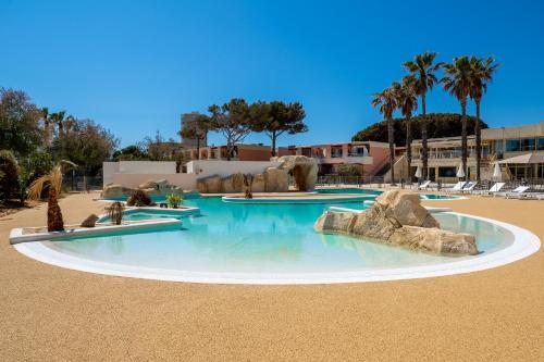 - une grande piscine avec des rochers dans un complexe dans l'établissement Village Club L'Oustal Del Mar, au Lavandou