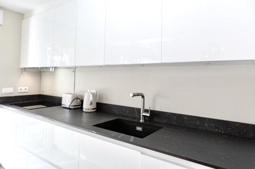 - une cuisine blanche avec un évier et des placards blancs dans l'établissement Belle villa familiale rénovée dans cadre exceptionnel-AG15, à Lacanau