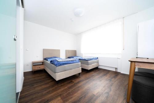 two beds in a room with wooden floors at Pension am Bahnhof in Nürtingen