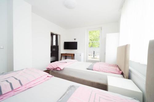 two beds in a white room with a window at Pension Diloyal in Nürtingen