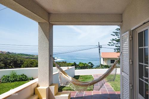 a hammock on the balcony of a house overlooking the ocean at Villa Castelo de Mar in Ericeira