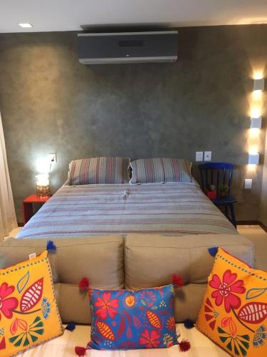 a bedroom with a bed with pillows on a couch at Studio Luxo Ecológico. in Maceió