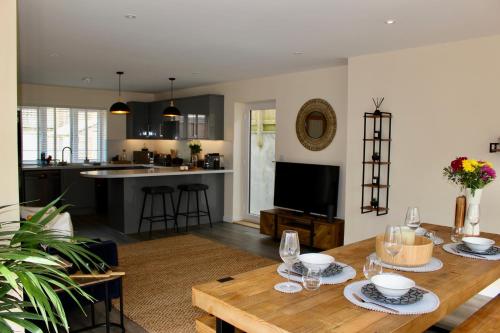 a kitchen and living room with a wooden table at No 1 The Paddock - Spacious holiday home with a hot tub in Bude
