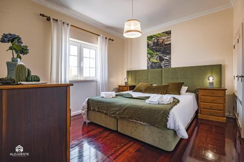 a bedroom with a large bed with a green headboard at Villa Castelo de Mar in Ericeira