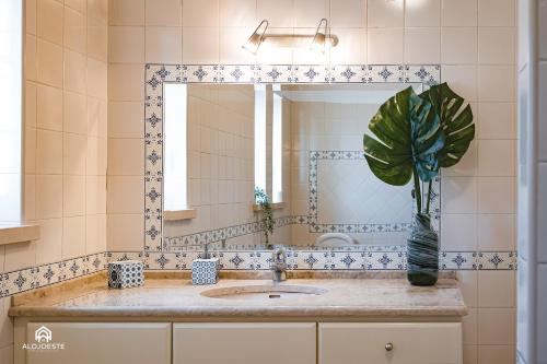 a bathroom with a sink and a mirror and a plant at Villa Castelo de Mar in Ericeira