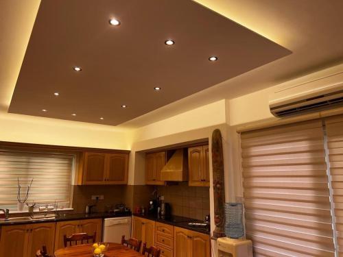 una cucina con armadi in legno e un soffitto con luci di AMAZING VILLA WITH BREATH TAKING VIEWS AND POOL a Limassol