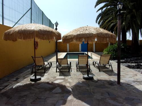 a patio with chairs and a table with umbrellas at Apartamentos Casa Rosán, junto a la Caldera de Taburiente in El Paso