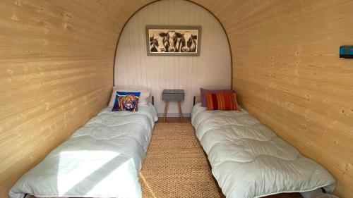 a room with two beds in a wooden wall at MotoCamp Wales -Camping Pods in Dolgellau