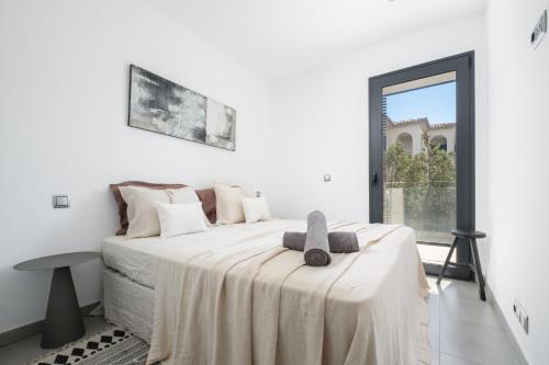 Un dormitorio blanco con una cama con una toalla. en La Perla Pollensa - BY EMERALD STAY, en Puerto Pollensa