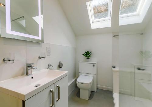 a white bathroom with a toilet and a sink at Seaview Moorings in Porthleven
