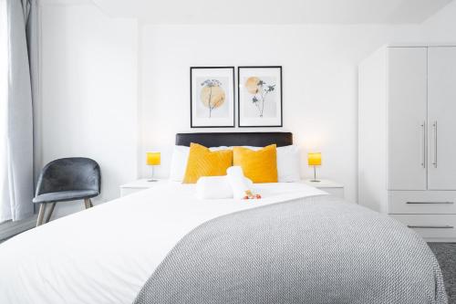 a white bedroom with a large bed with orange pillows at Opulent 2 Bedroom City Centre Apartment in Nottingham