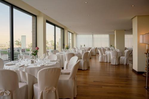 リミニにあるナショナル ホテルの白いテーブルと椅子、窓のある宴会場