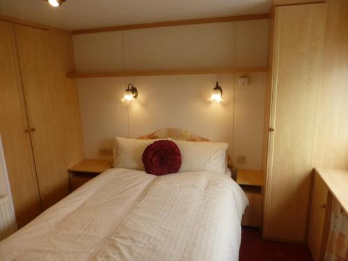 a bedroom with a white bed with a red pillow on it at 73 Port Haverigg in Millom