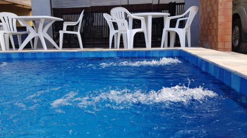 a pool with white chairs and water in it at Triplex de veraneio em Guaratuba in Guaratuba