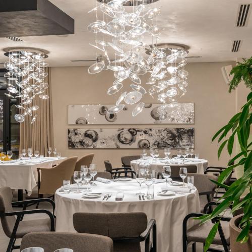 a restaurant with white tables and chairs and a chandelier at Monograph Freedom Square in Tbilisi City