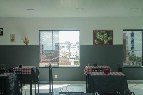 a dining room with two tables and two windows at HOTEL Al ATLANTICO in Aracaju
