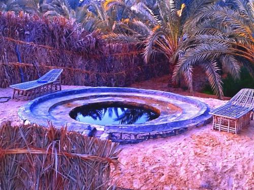 a painting of a pool with two chairs and palm trees at Nashdeen Eko Lodge in ‘Izbat Zaydān