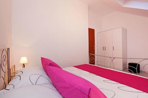 um quarto com uma cama grande e almofadas cor-de-rosa em Apartments Park em Vela Luka