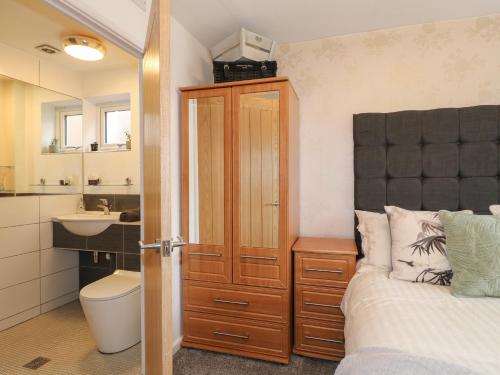 a bedroom with a bed and a bathroom with a sink at Lavender Lodge in Coalville