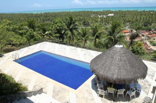 an aerial view of a resort swimming pool with a straw umbrella at Maravilhosa Mansão na Praia de Ipioca in Maceió