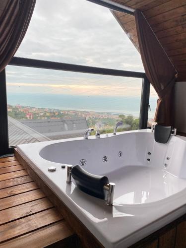 a white bath tub in a room with a large window at VİLLA DENİZ , KiRAZ in Trabzon