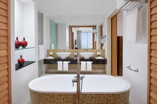 a bathroom with a tub and two sinks at Mövenpick Hotel Jumeirah Beach in Dubai