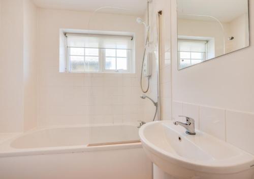 a bathroom with a sink and a tub and a mirror at Brock Cottage in Instow