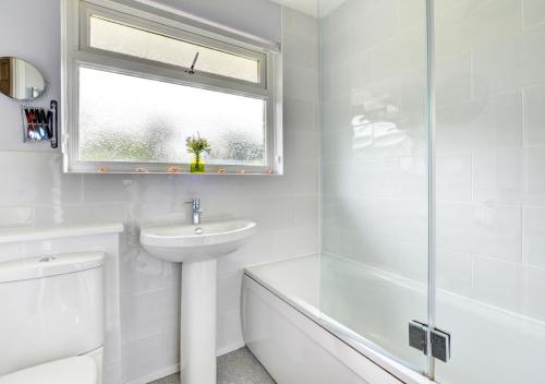 a white bathroom with a sink and a bath tub at Burrows Retreat in Braunton