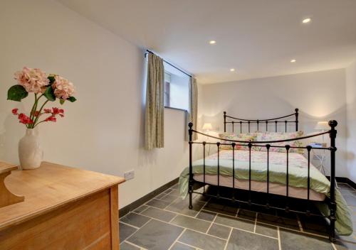 a bedroom with a bed and a vase with flowers at Bramble Cottage in Barbrook