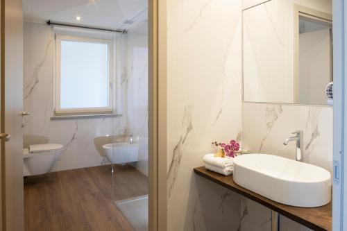 W białej łazience znajduje się umywalka i lustro. w obiekcie CASCINA SANT'ANTONIO w Albie