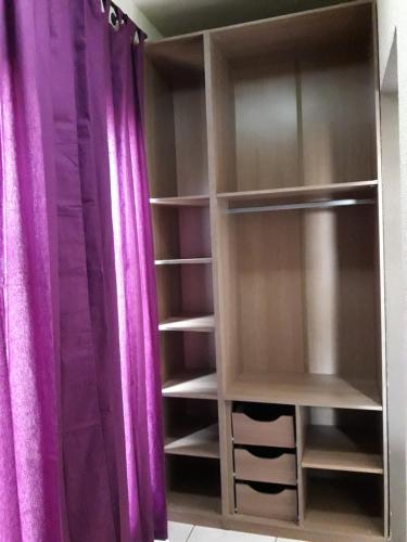 a room with purple curtains and a closet with shelves at Triplex de veraneio em Guaratuba in Guaratuba