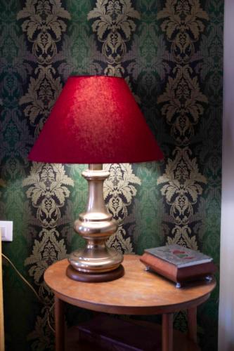 a red lamp sitting on a table with a book at La Maisonette in Feltre