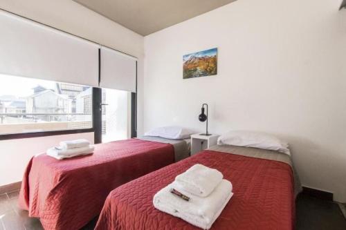 2 camas en una habitación con sábanas rojas y toallas en Gente del Sur - Fuego en Ushuaia