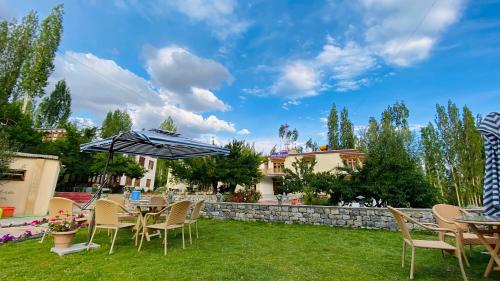 a patio with tables and chairs and an umbrella at Hotel Palam Hills in Leh