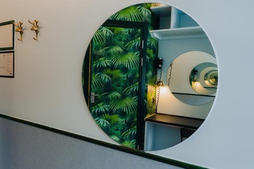 a mirror on a wall with a room with a green plant at Copenhagen Downtown Hostel in Copenhagen