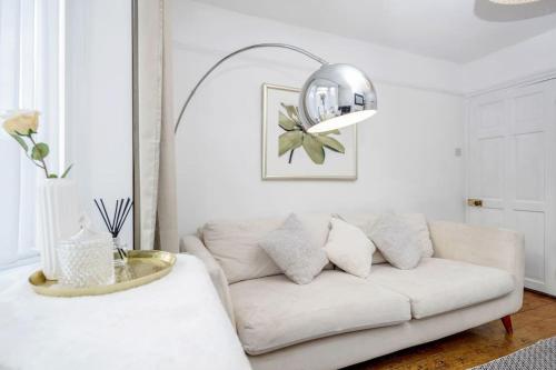 a living room with a white couch and a mirror at Stylish Victorian 3 Bed House Huge Garden/Parking in Staines