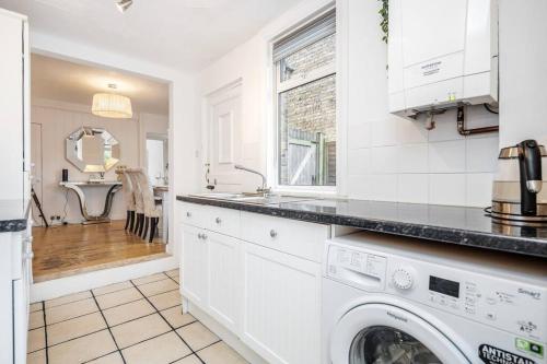 a white kitchen with a washer and dryer at Stylish Victorian 3 Bed House Huge Garden/Parking in Staines