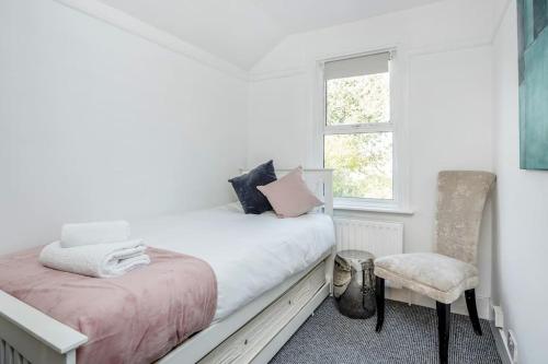 a white bedroom with a bed and a chair at Stylish Victorian 3 Bed House Huge Garden/Parking in Staines