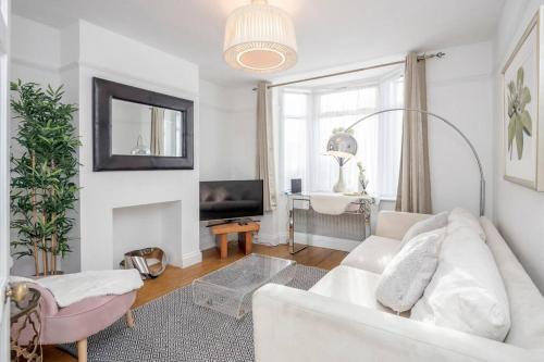 a living room with a white couch and a tv at Stylish Victorian 3 Bed House Huge Garden/Parking in Staines
