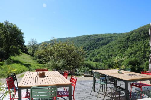 two tables and chairs on a deck with mountains in the background at Oltarcie - Maison d'hôte avec piscine in Espagnac-Sainte-Eulalie