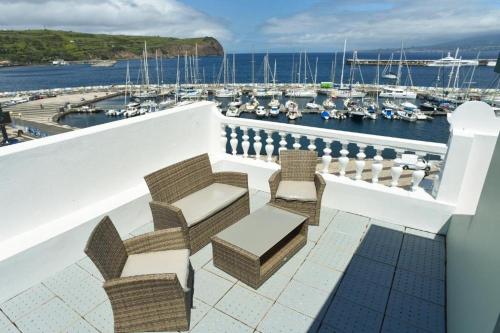 einen Balkon mit Stühlen und Blick auf den Yachthafen in der Unterkunft Internacional Azores Boutique in Horta