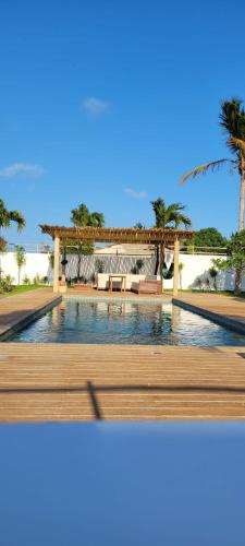 a swimming pool with a wooden deck and palm trees at Casa Pordosol in Fortim