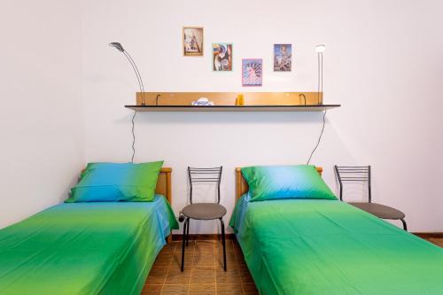 two beds in a room with green sheets and chairs at La Romana Antica in Madonna di Fornelli