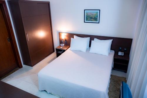 a bedroom with a large bed with white sheets and pillows at Hotel Santos Dumont in Goiânia
