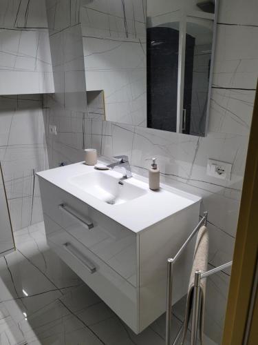 a white bathroom with a sink and a mirror at La finestra sul corso in Ortona