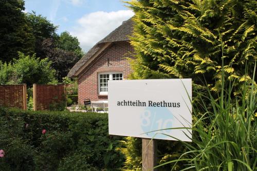 un panneau en face d'un jardin avec une maison dans l'établissement Ferienwohnung Reethuus 6, FeWo Vermittlung Nordsee, à Dangast