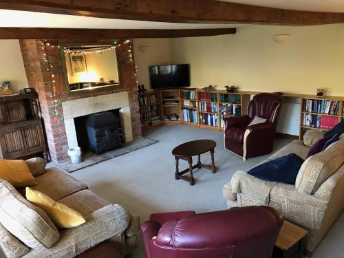 Converted Coach House Holt, Wiltshire في Holt: غرفة معيشة مليئة بالأثاث ومدفأة