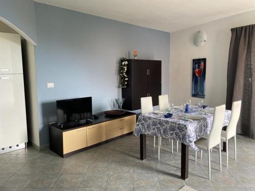 a dining room with a table with chairs and a tv at APPARTAMENTO VISTA MARE CASTELSARDO in Castelsardo