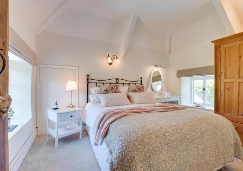 a white bedroom with a large bed and a window at Court Cottage in Berrynarbor